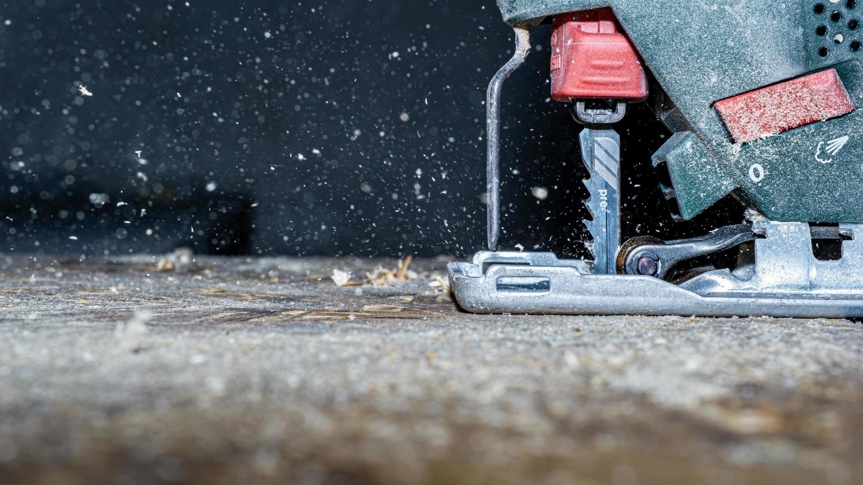 Nahaufnahme der elektrischen Stichsäge, die ein Stück Holz schneidet foto