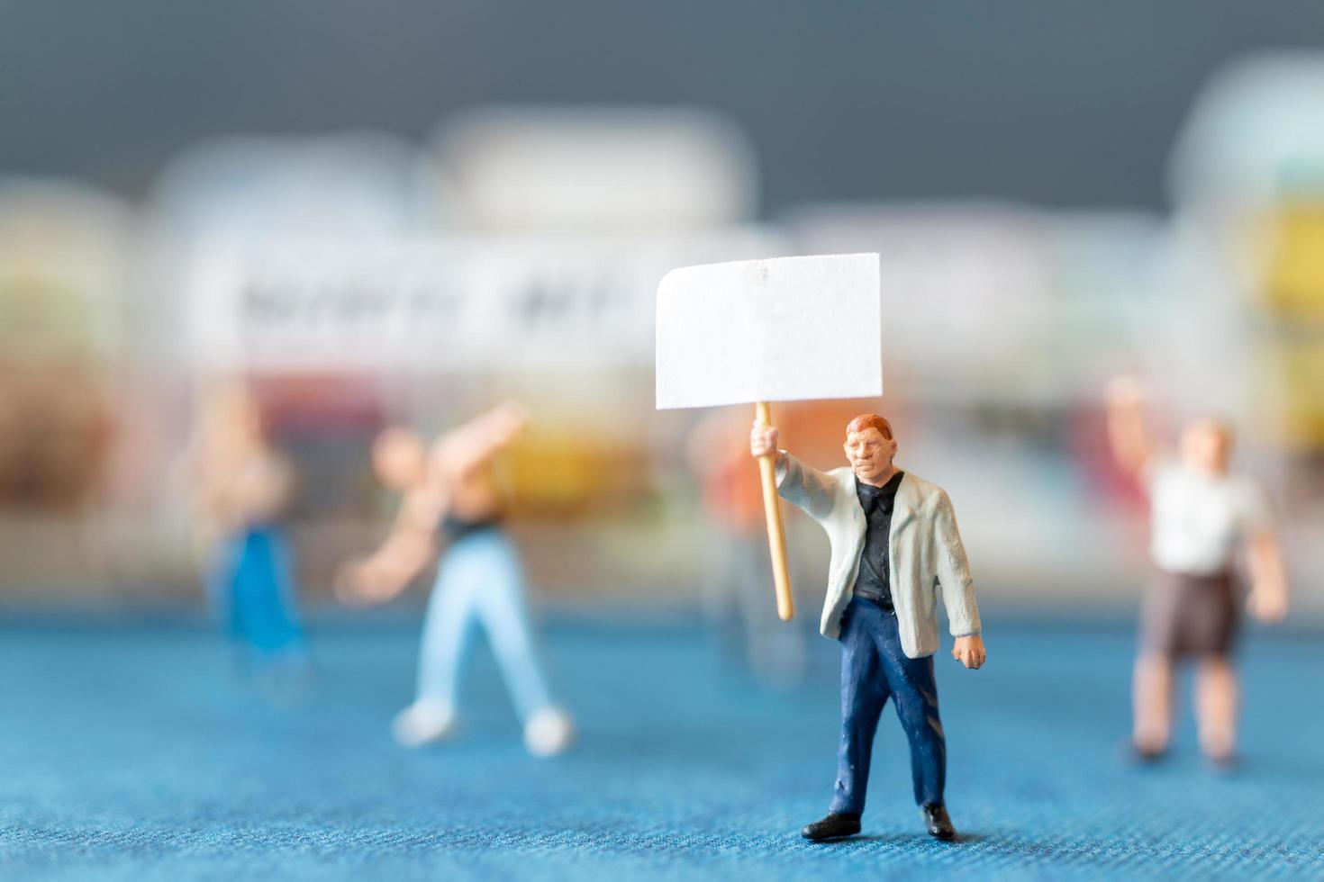 Miniaturmenschen, Demonstranten, die Schilder halten, ihre Hände für die Revolution heben, gegen das Konzept protestieren foto