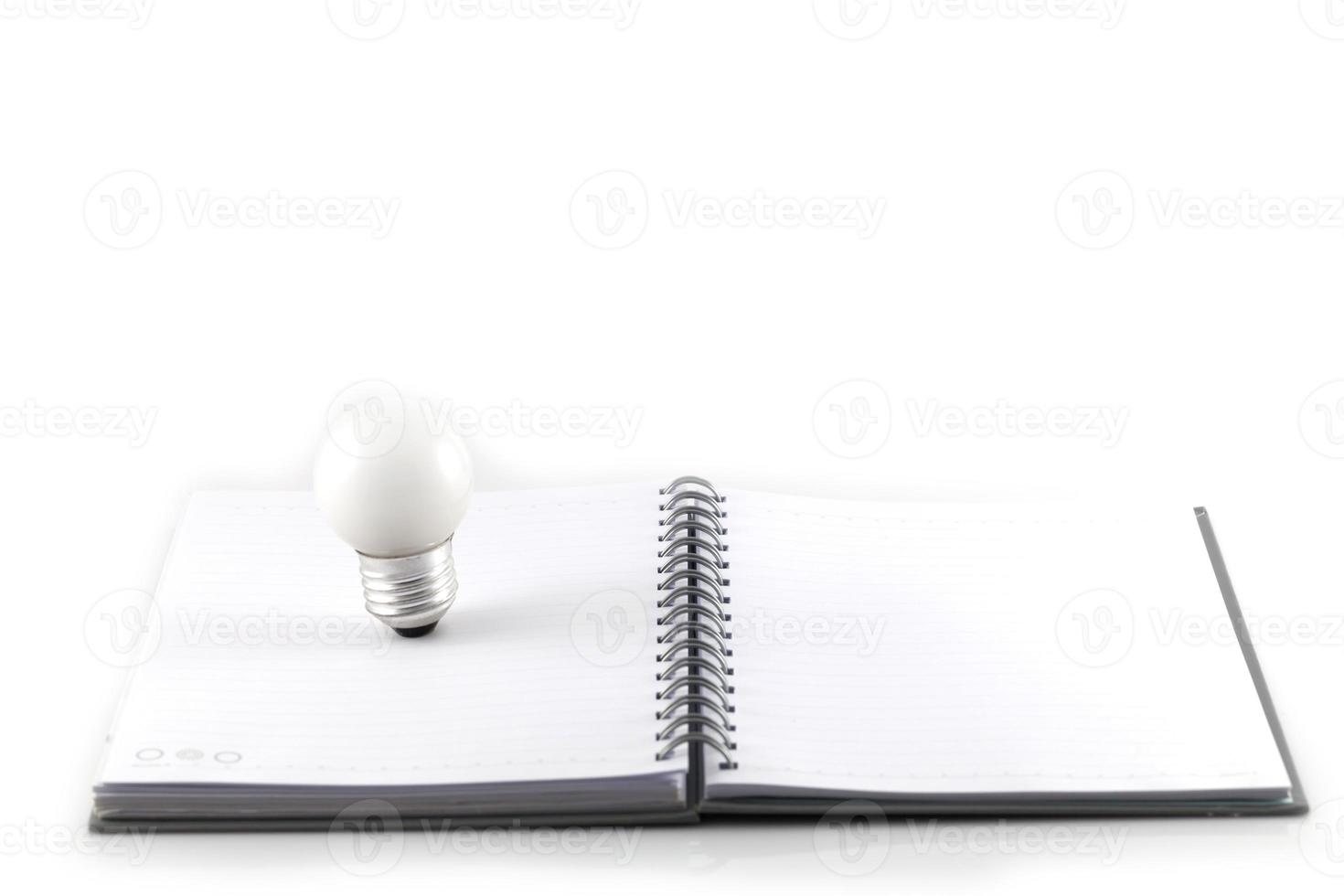 Notizbuch und Glühbirne lokalisiert auf einem weißen Hintergrund foto