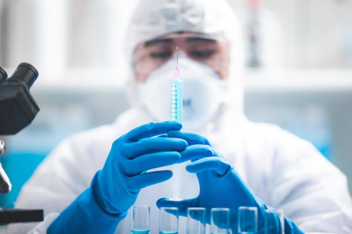 Wissenschaftler hält eine Spritze mit blauer Flüssigkeit darin foto