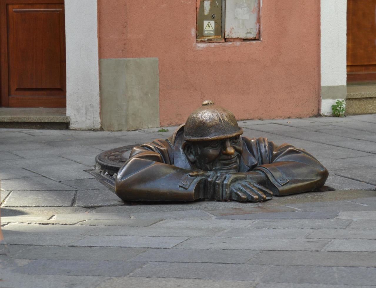 cumil Statue, ein gutmütiger Mann, der arbeitet und einen Abwasserkanal verlässt foto