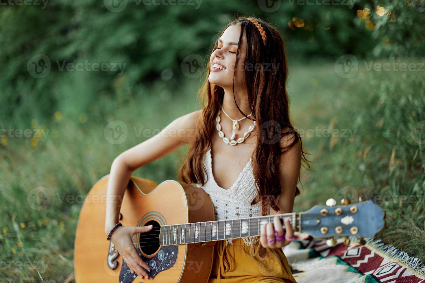 Hippie Frau lächelnd und umarmen ihr Gitarre im Natur im das Park im das Sonnenuntergang Licht im Öko-Kleidung foto