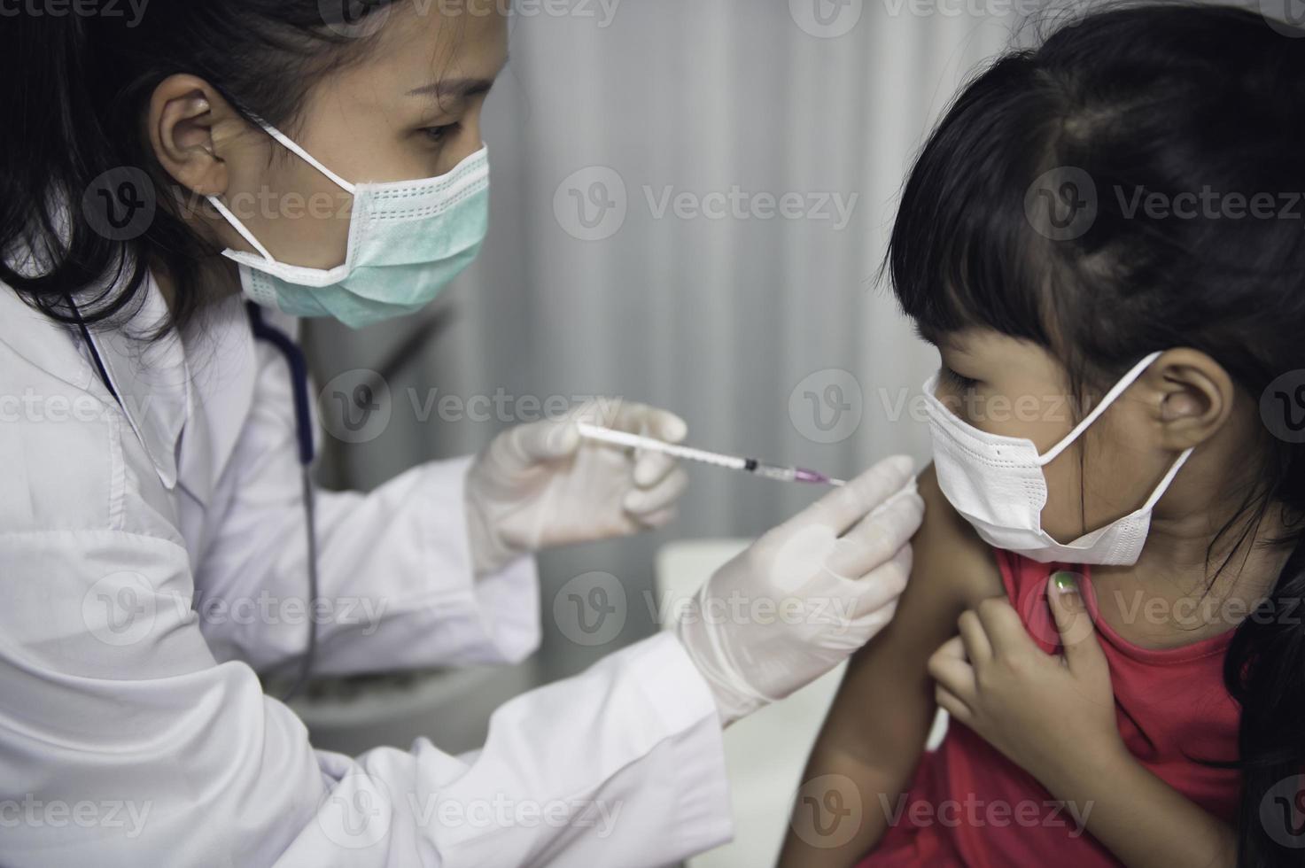 asiatisch Arzt Injektion Impfstoff zum schützen Virus covid-19 zu ein Mädchen tragen medizinisch Maske, Leute sind Mädchen sind geimpft gegen Grippe jeder Jahr. foto