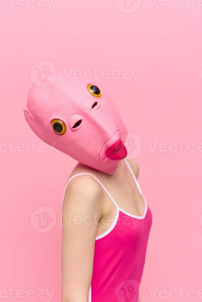 modern Halloween Kostüm im ein Silikon Maske im das gestalten von ein Rosa Fisch Kopf im ein sexy Kostüm. das Konzept von ein verrückt aussehen foto