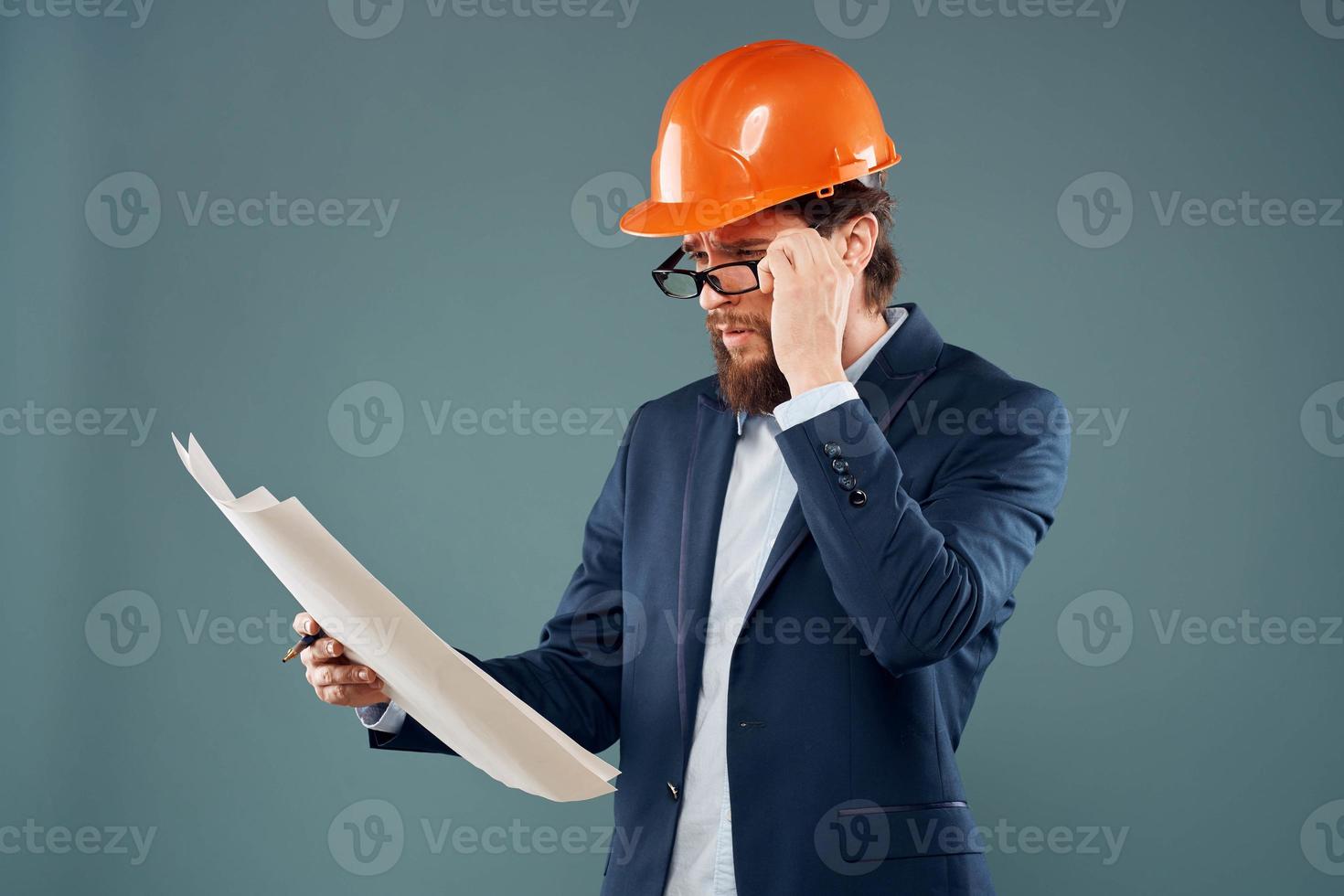 ein Mann im Orange Farbe Blaupausen im das Hände von ein Konstruktion Industrie offiziell foto