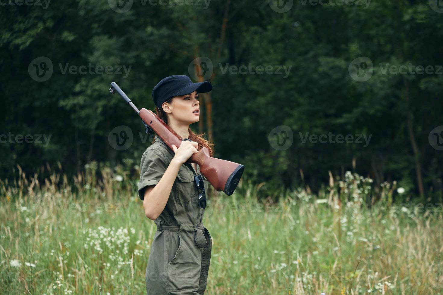 Frau mit ein Gewehr auf seine Schulter, ein schwarz Deckel ist ein Weg von Leben zum Jagd Grün Overall foto