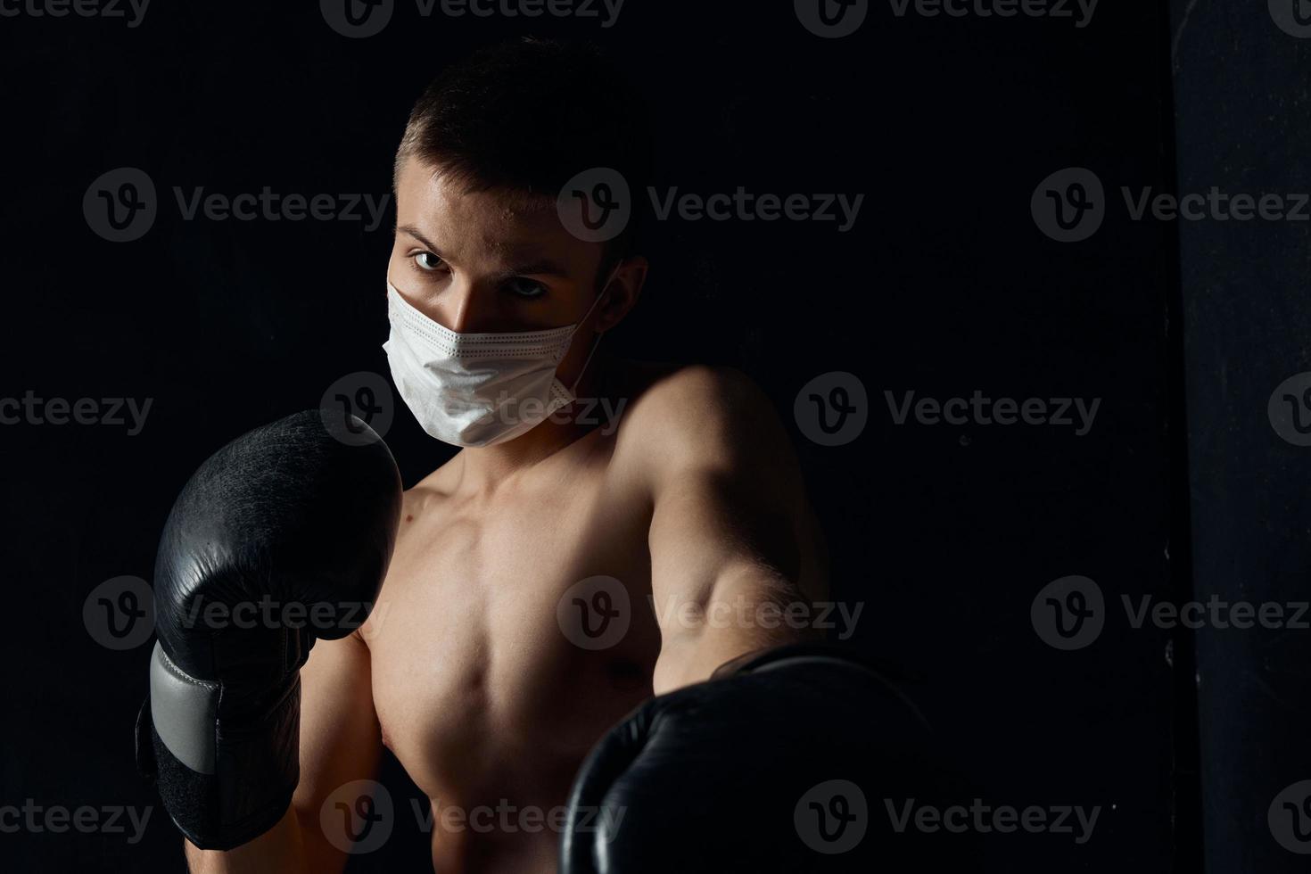 Boxer im ein medizinisch Maske und Boxen Handschuhe auf ein schwarz Hintergrund foto