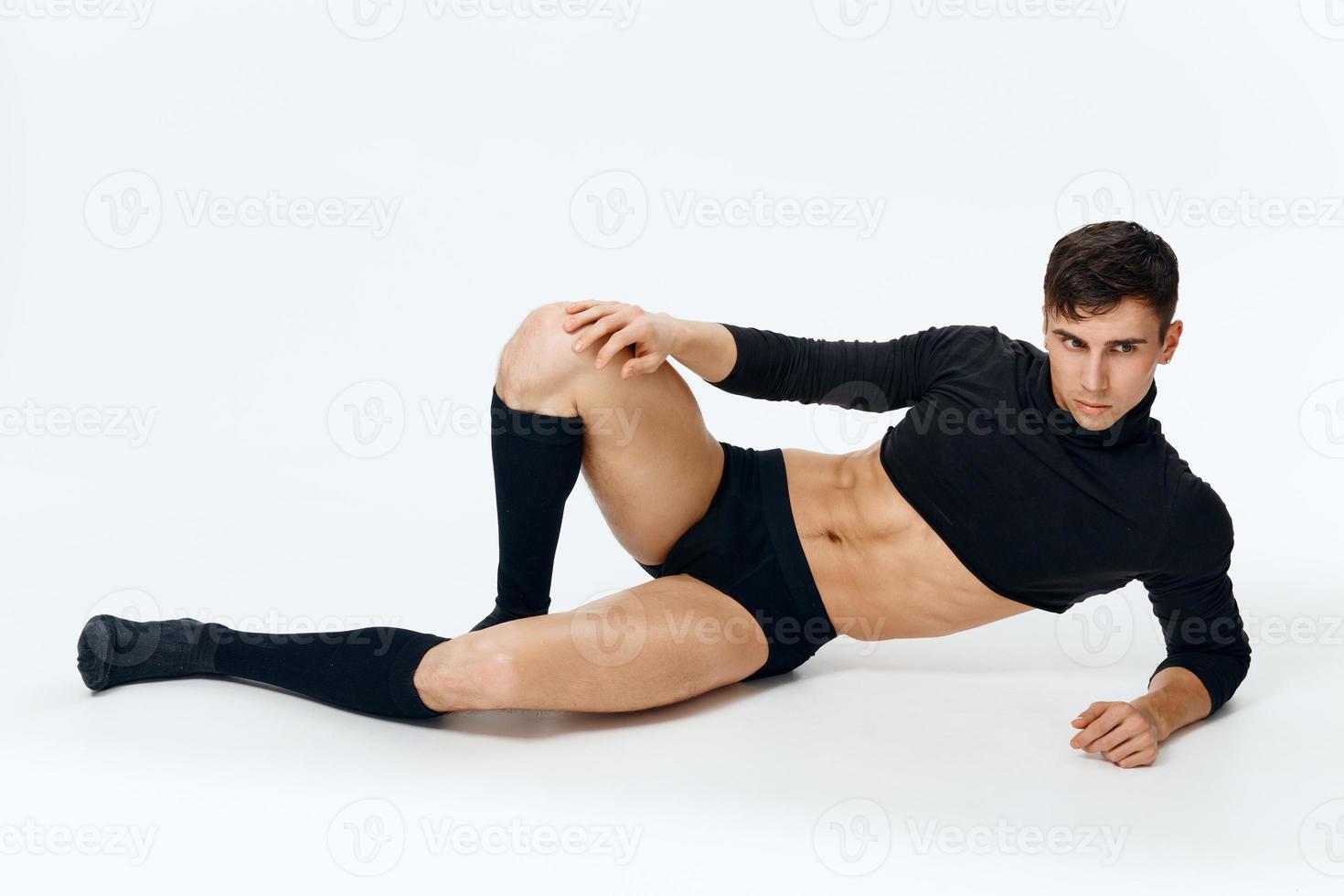 ein Kerl mit ein aufgepumpt Torso im ein Sweatshirt kurze Hose und Socken Lügen auf das Fußboden foto