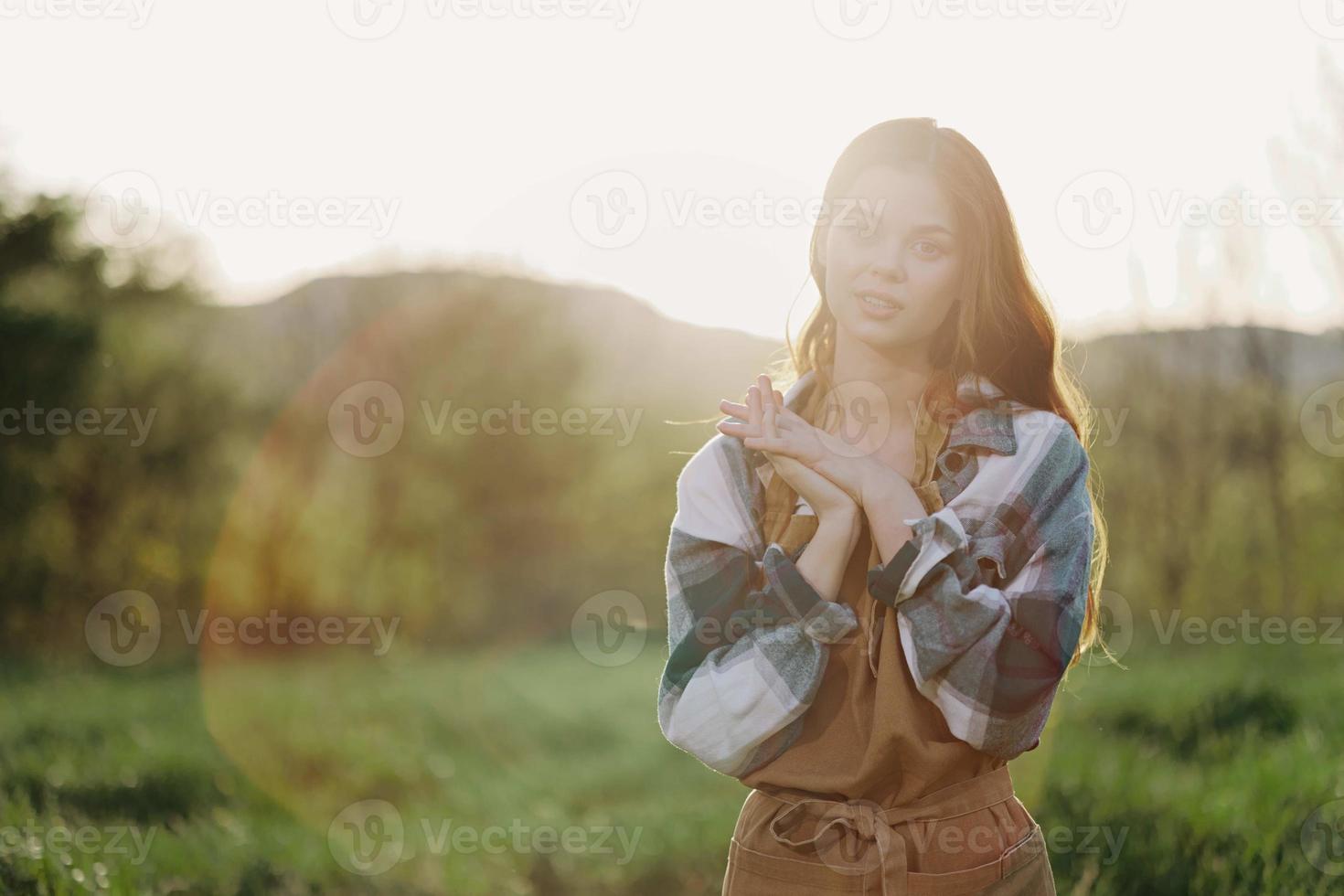 Porträt von ein jung lächelnd Frau im Arbeit Kleider kariert Hemd und Schürze im Natur im das Abend nach Arbeit foto