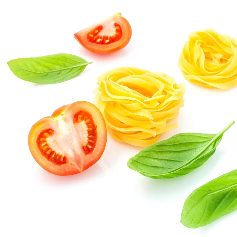 italienisches Nahrungsmittelkonzept der Fettuccine mit Tomate und süßem Basilikum lokalisiert auf einem weißen Hintergrund foto