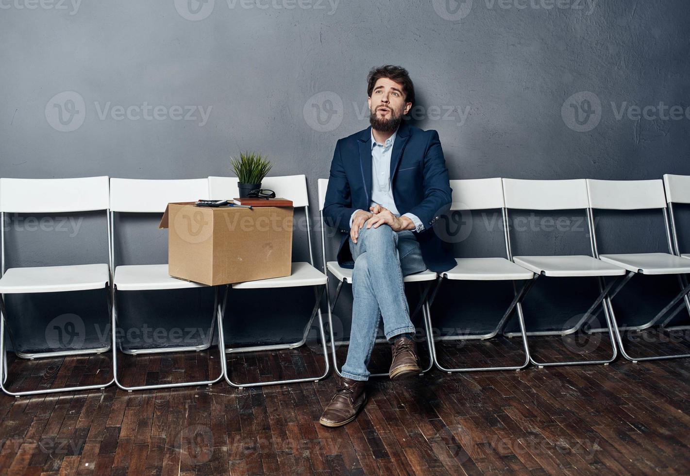 ein Mann im ein passen sitzt auf ein Stuhl mit ein Box Job Suche Depression foto