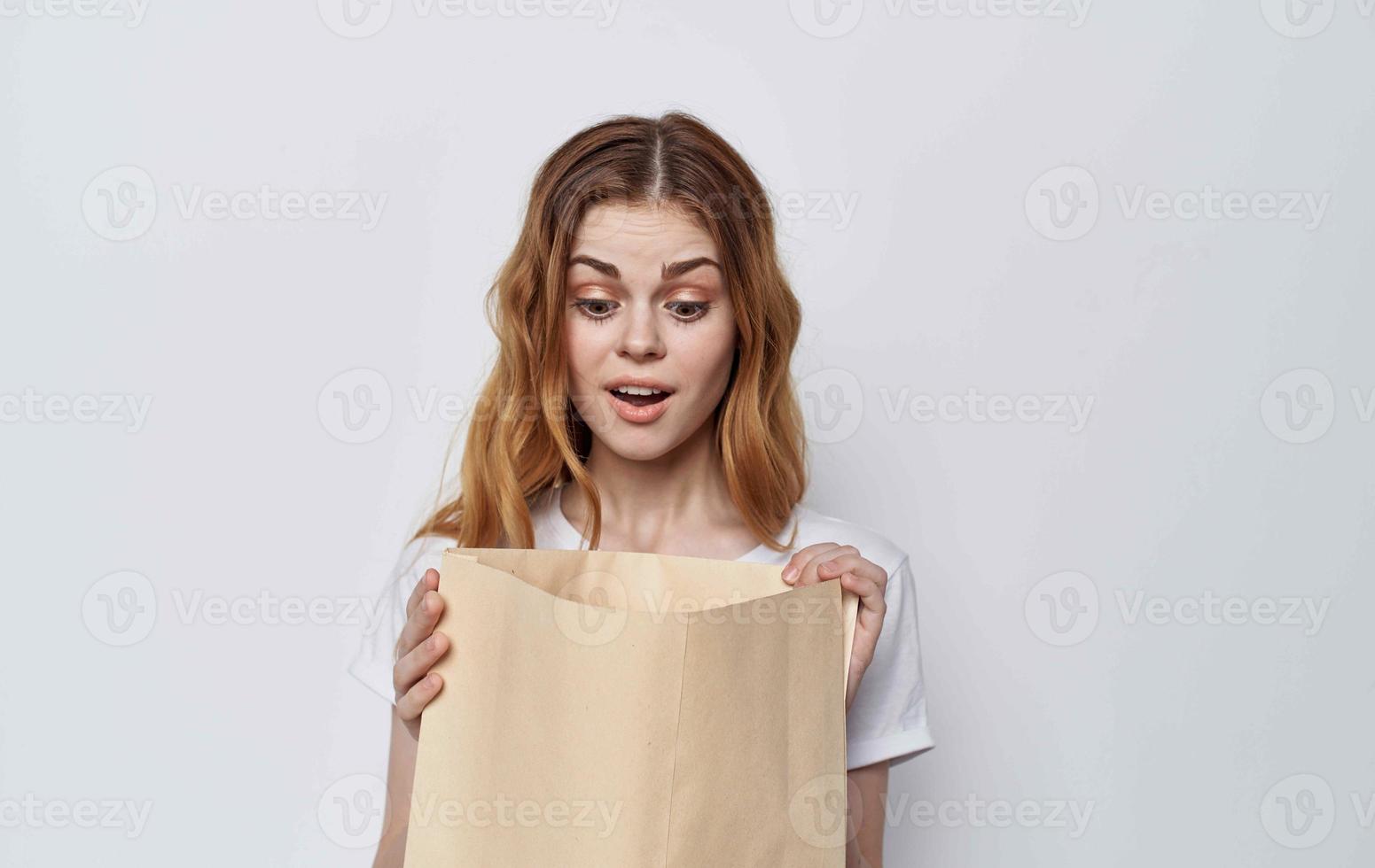 Frau im ein Weiß T-Shirt mit ein Paket im ihr Hände Einkaufen foto