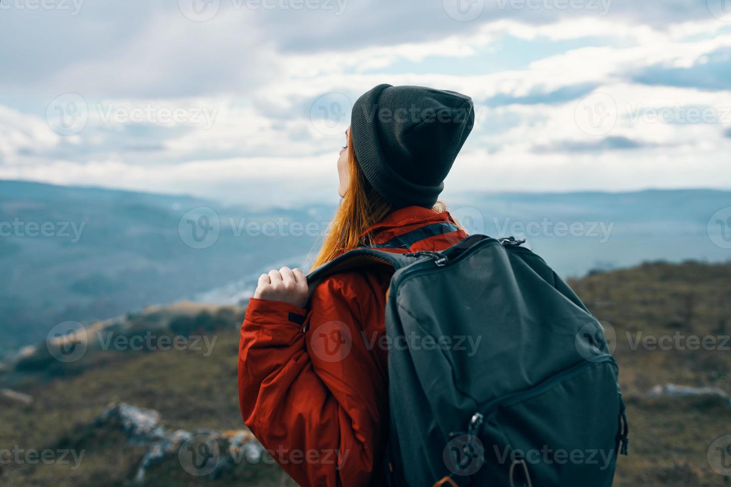 energisch Frau im warm Kleider mit Rucksack Reise Tourismus Berge Landschaft zurück Aussicht foto