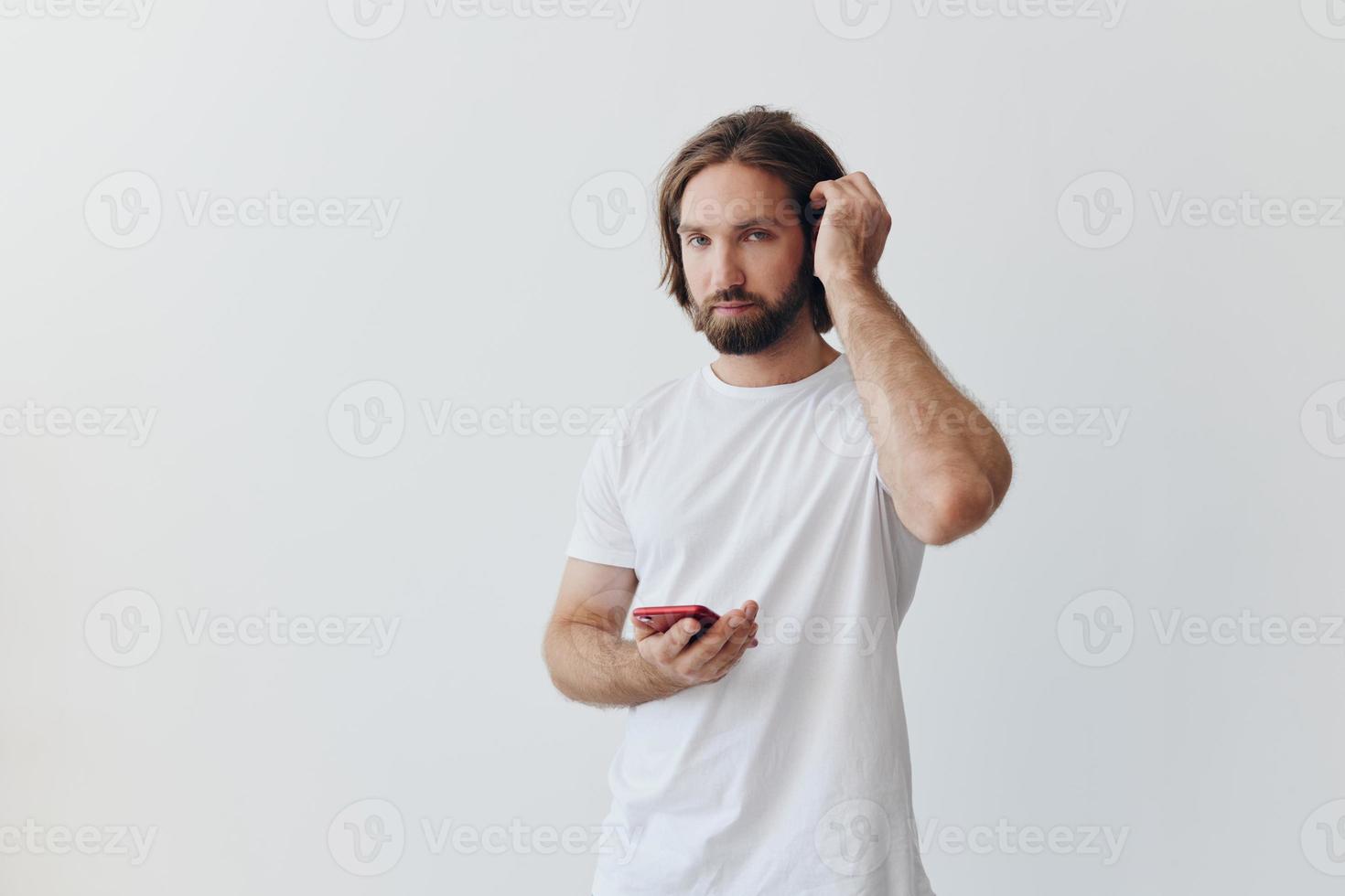 ein Mann ist halten ein Telefon mit kabellos Kopfhörer im seine Ohren und lesen ein Sozial Medien Botschaft online Freiberufler Job Korrespondenz auf ein Weiß Hintergrund foto