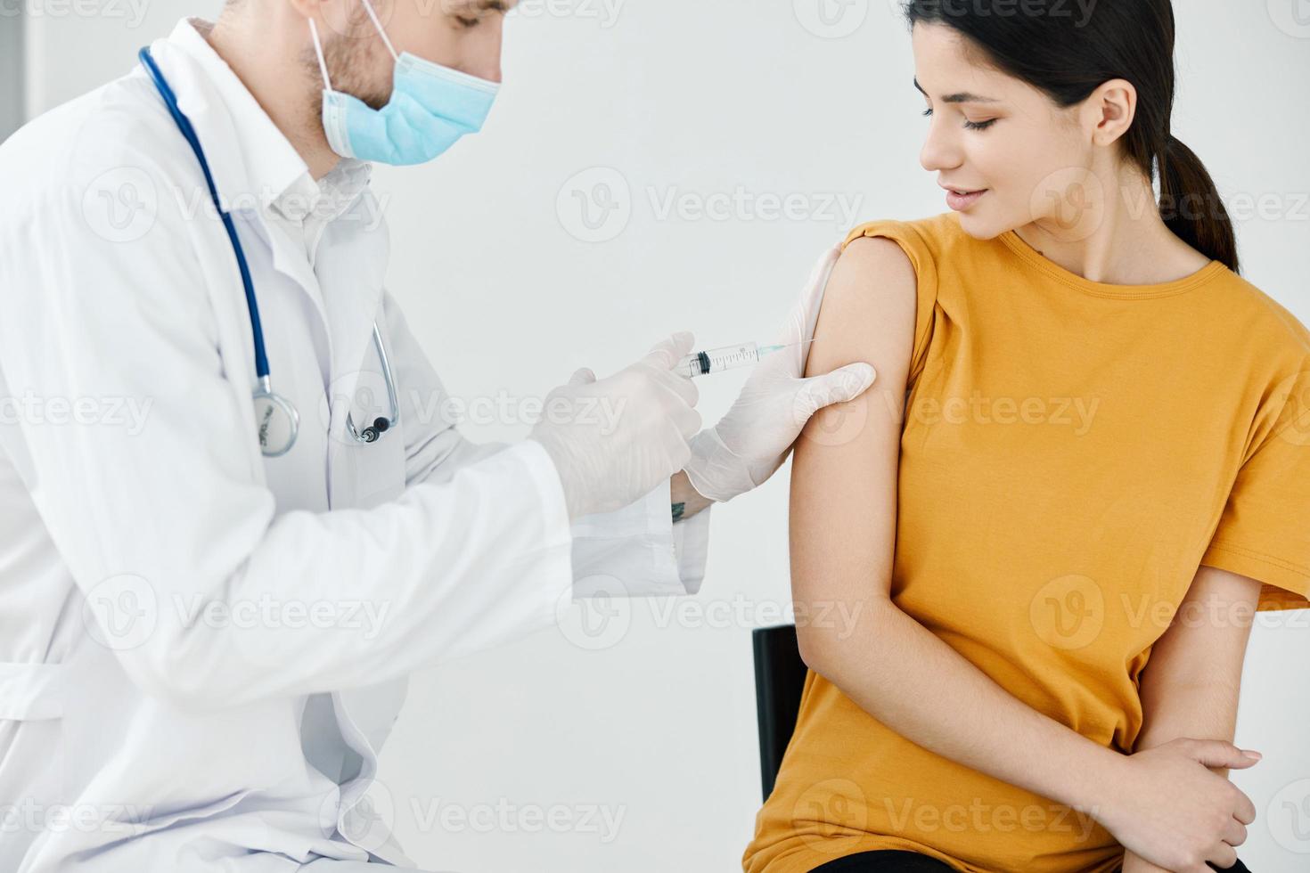 ein Arzt im schützend Handschuhe zu Stock ein Injektion Gips auf ein Frau covid Impfung foto