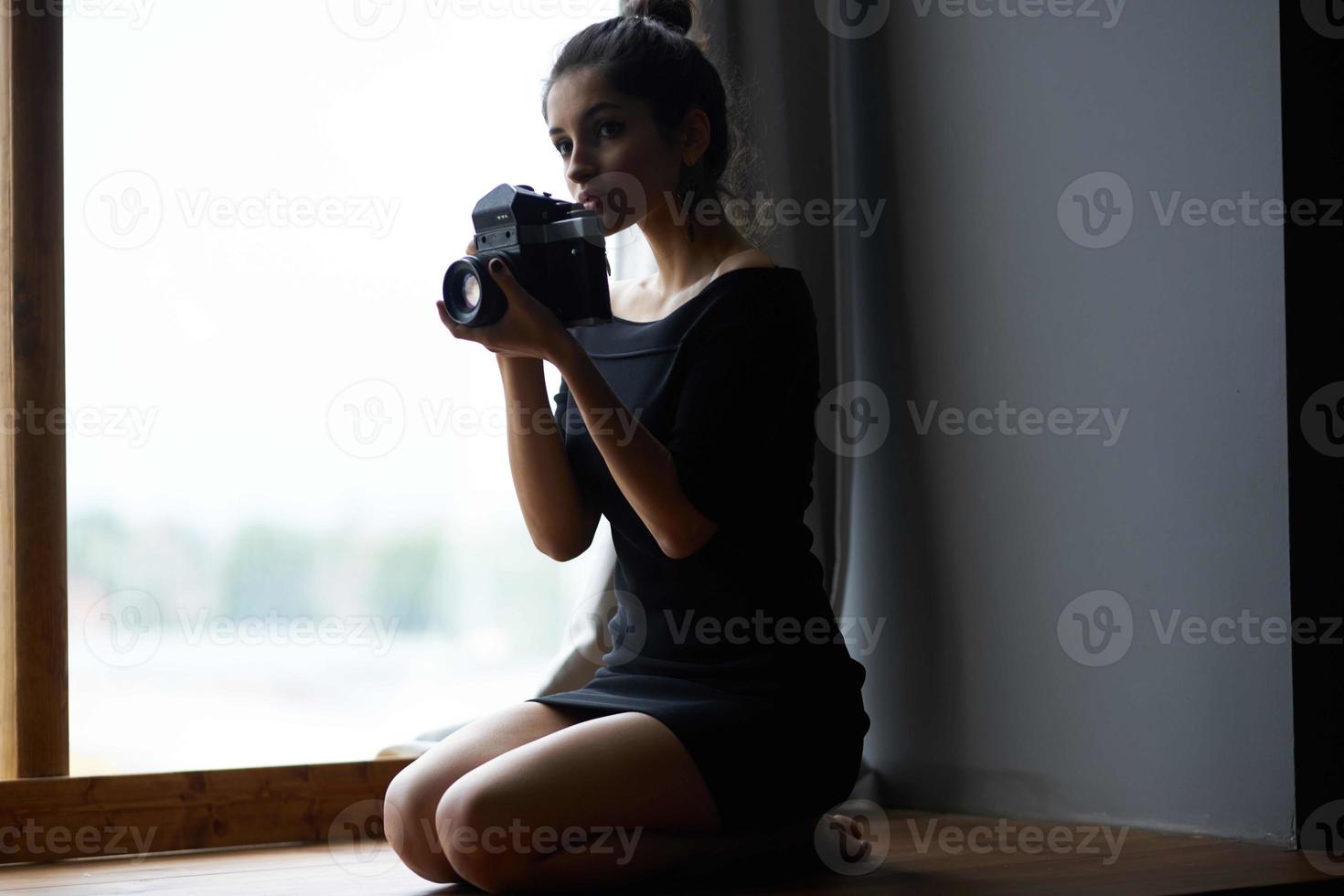 schön Frau halten ein Kamera in der Nähe von das Fenster Dekoration Mode Lebensstil Studio foto