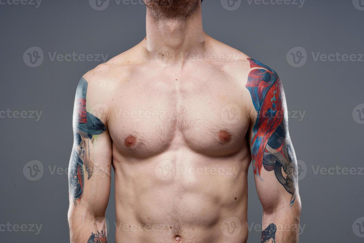 sportlich Mann mit gepumpt oben Abs Tätowierungen auf seine Waffen grau Hintergrund Muskeln foto