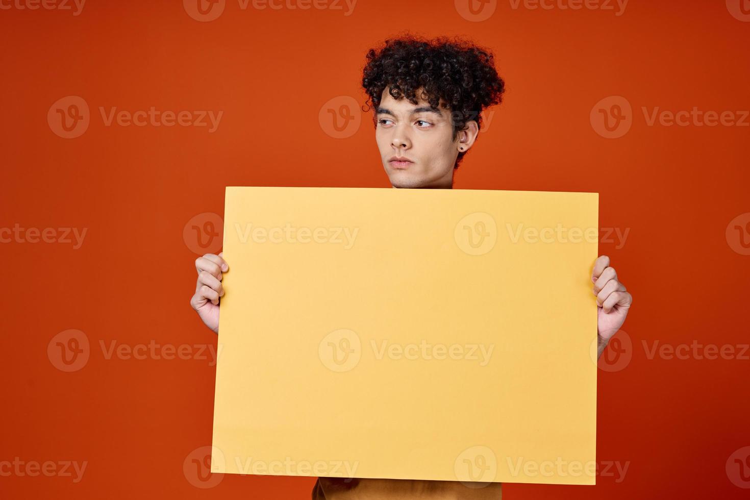 Kerl mit lockig Haar Gelb Poster im Hände Studio Werbung foto