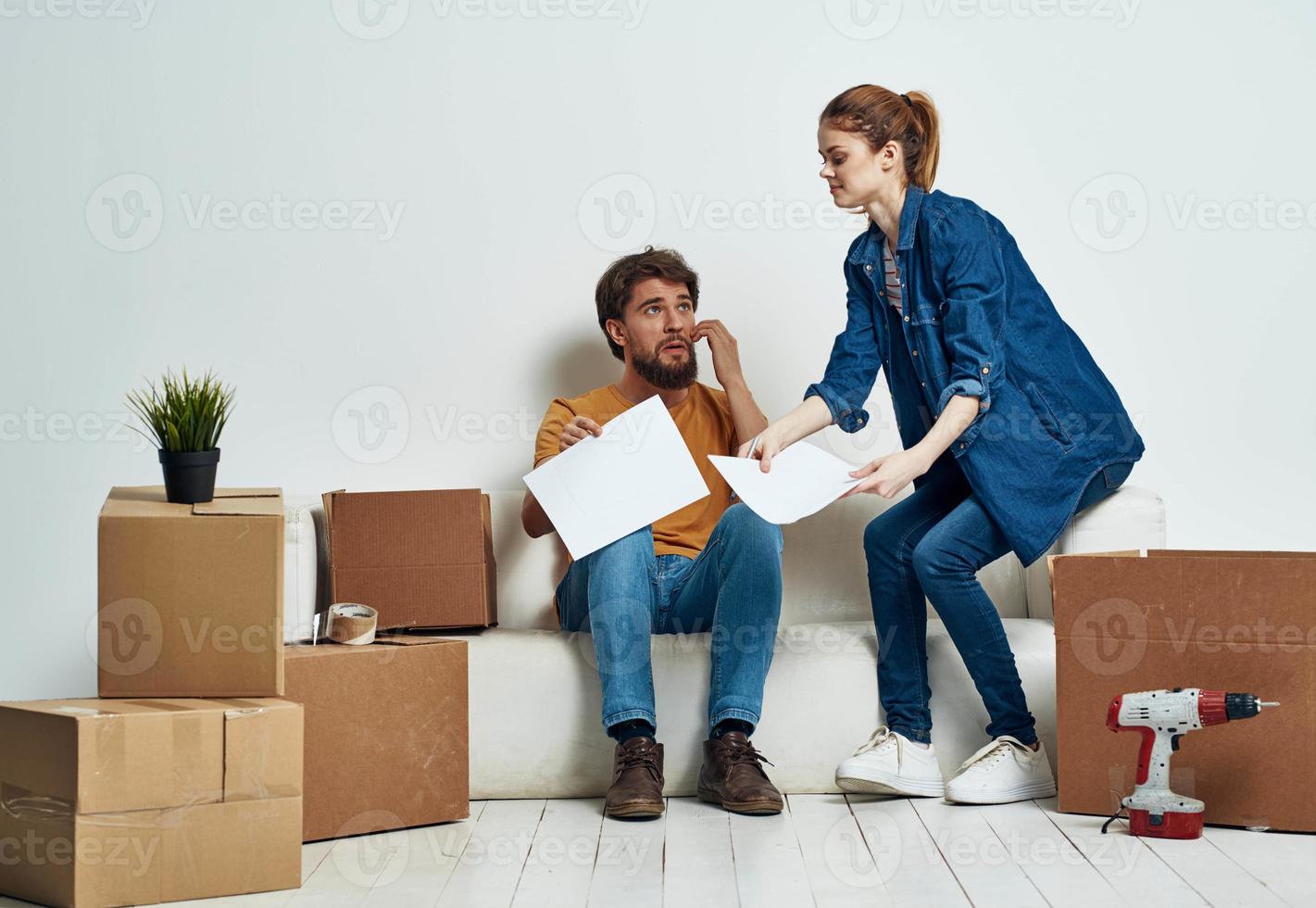 jung Paar auf Weiß Couch mit Kisten von Spaß chatten foto