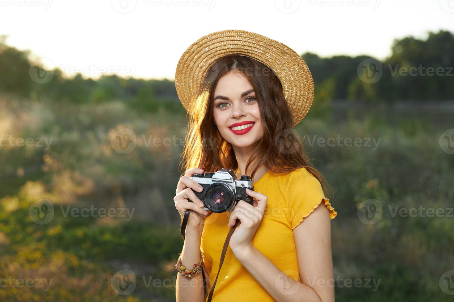 ziemlich Frau rot Lippen Charme Hut auf ihr Kopf ein Kamera im das Hände von ein Hobby foto