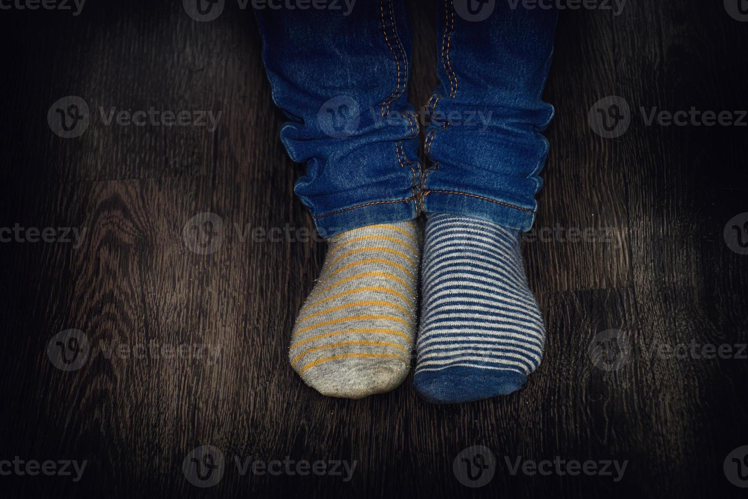 zwei Jungs Füße gekleidet im verschiedene gestreift Socken auf ein hölzern Fußboden foto