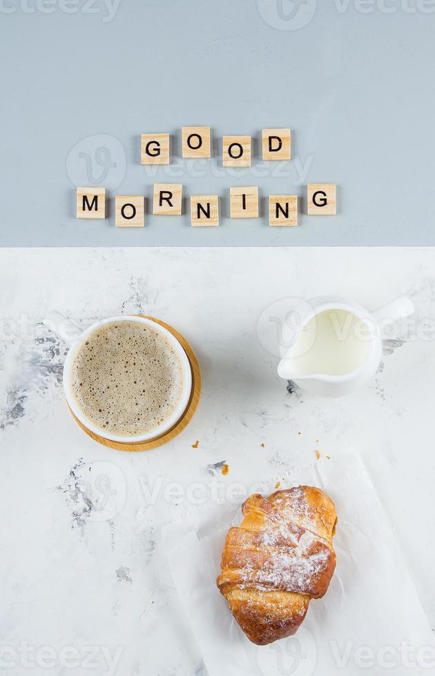 gut Morgen Frühstück minimal Konzept. Tasse von Kaffee, Croissant und Text gut Morgen. eben legen foto