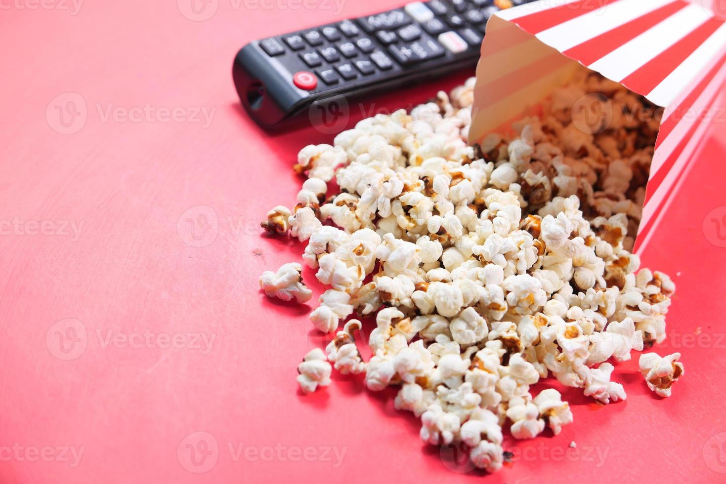 Popcorn und TV-Fernbedienung auf rotem Hintergrund foto