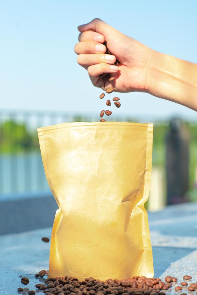Hand Kaffeebohnen in die papierbraune Tasche ohne Etikett freigeben foto