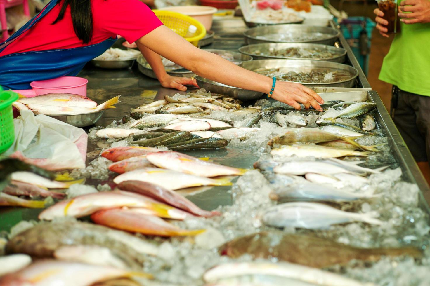 Selektiver Fokus auf die Hände des Verkäufers, der rohen frischen Fisch pflückt foto