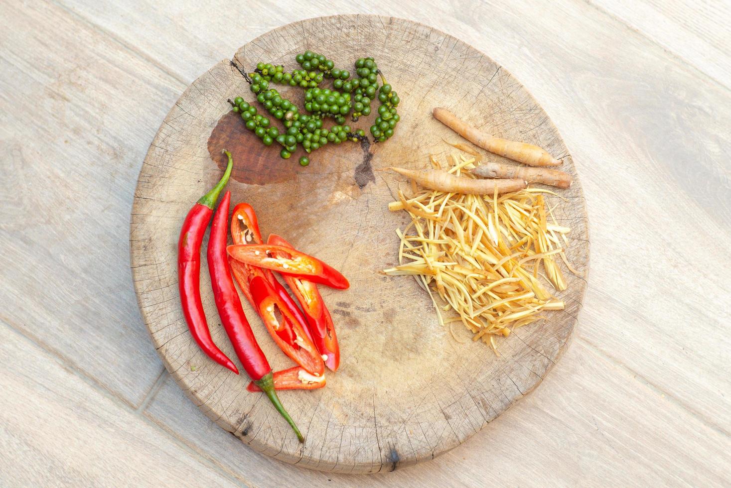 Draufsichtbild von Chili, Fingerwurzel und Pfeffer auf dem Holzteller foto