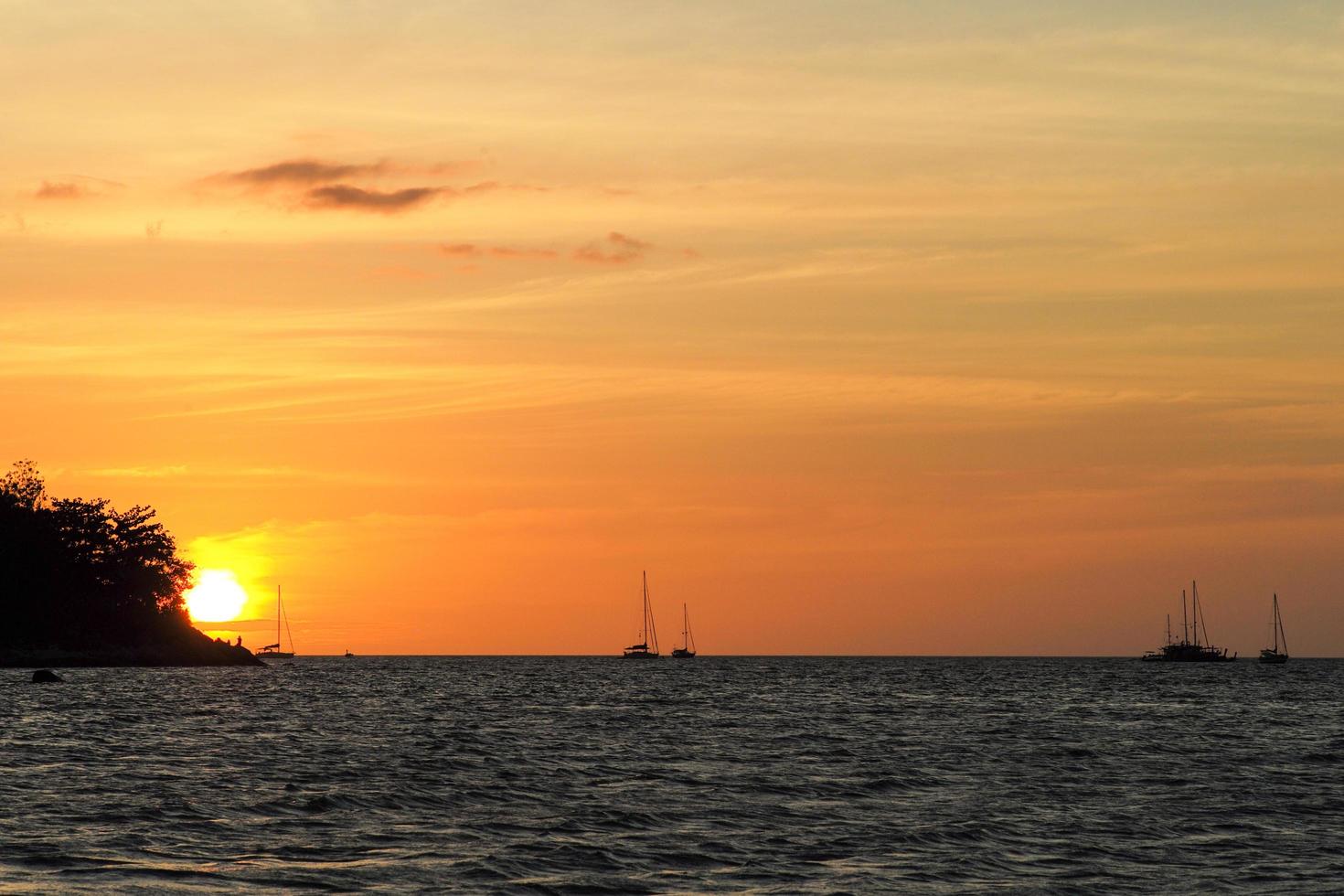 Silhouette der Insel und der Yachten am Horizont mit Licht des Sonnenuntergangs foto