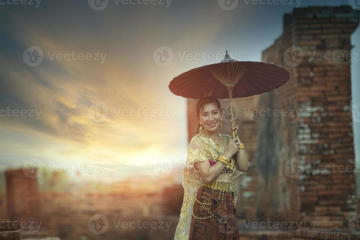 schön asiatisch Frau halten Bambus Regenschirm Stehen gegen alt Tempel im Ayutthaya Welt Erbe Seite? ˅ von UNESCO Thailand foto