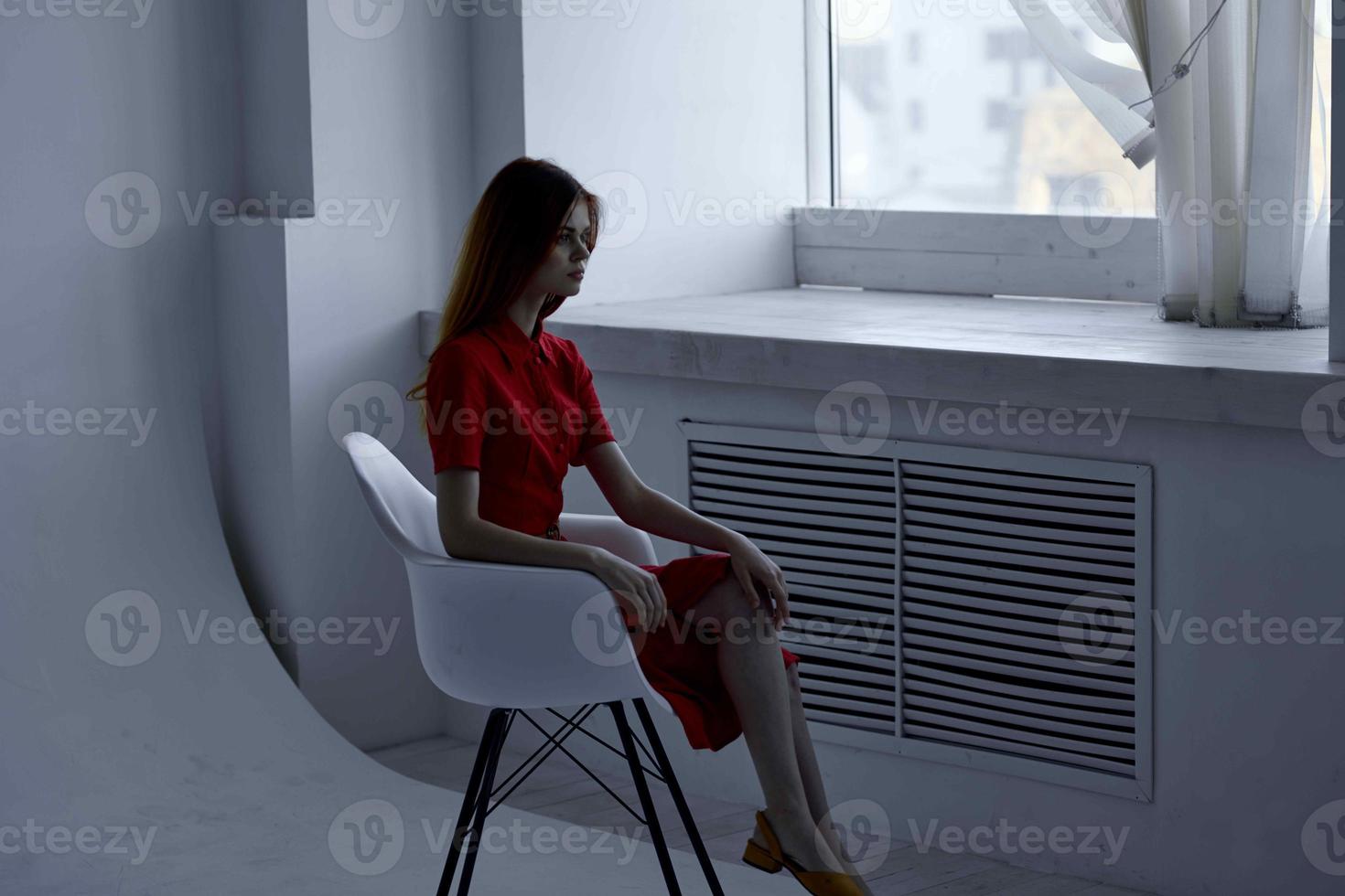 schön Frau im rot Kleid Sitzung in der Nähe von das Fenster elegant Stil foto