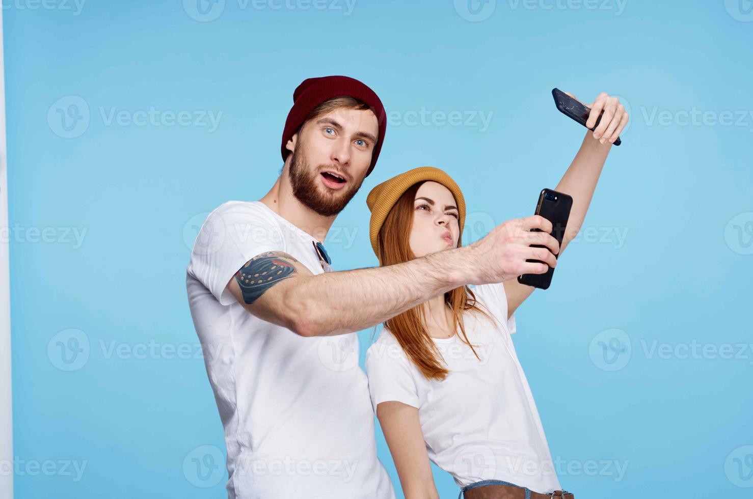 jung Paar getötet im T-Shirts mit Telefone im ihr Hände modern Technologie foto