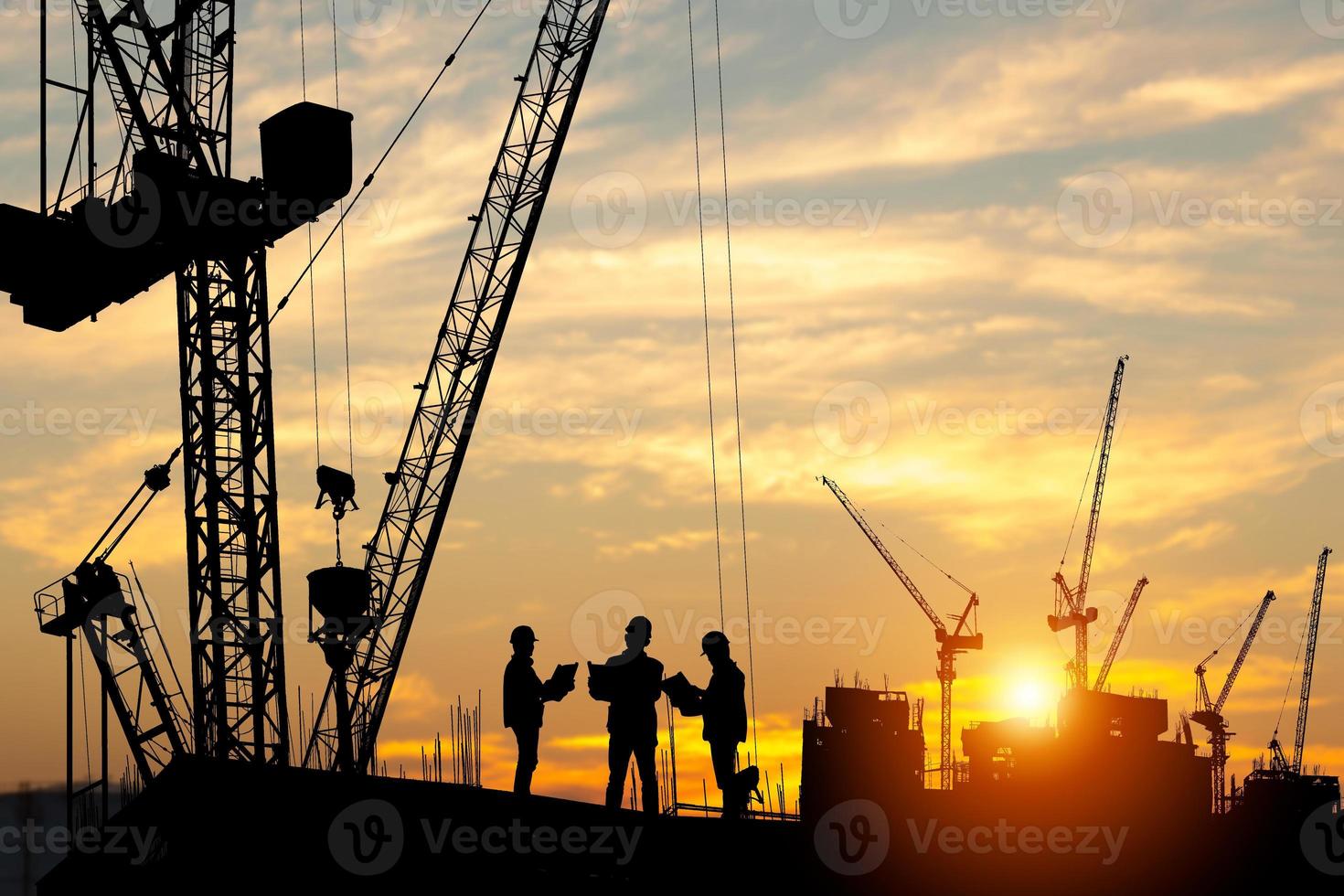 Silhouette von Ingenieur und Arbeiter Mannschaft auf Gebäude Grundstück, Konstruktion Seite? ˅ beim Sonnenuntergang im Abend Zeit foto