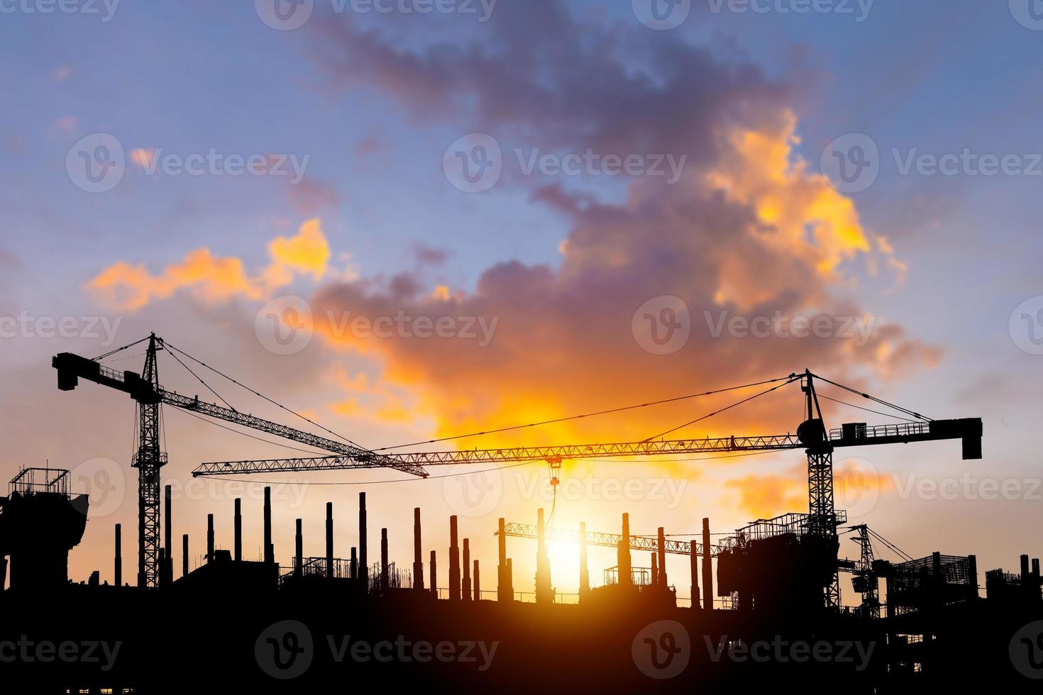 Silhouetten von Gebäude Konstruktion Seite? ˅ und Konstruktion Kräne mit Sonnenuntergang Hintergrund foto