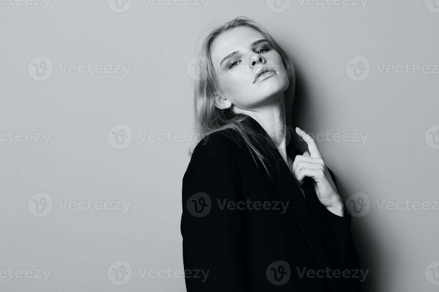 sexy ausdrucksvoll Fachmann Modell- berühren ihr Jacke und sieht aus beim Kamera. schön blond Dame posieren beim Studio. gut Angebot zum Mode Marken. minimalistisch Kunst Stil foto