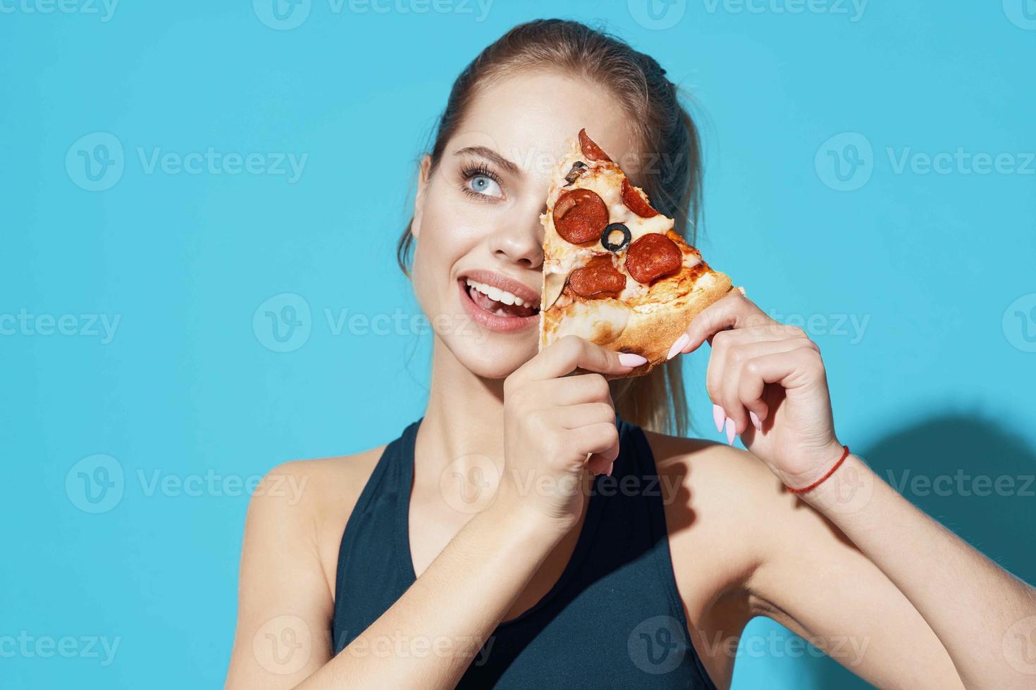 Frau im Sport Uniform Essen Pizza Essen Diät Blau Hintergrund foto