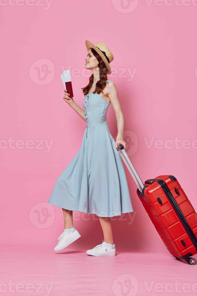 Frau im Blau Kleid mit rot Koffer Reise Ziel Rosa Hintergrund foto