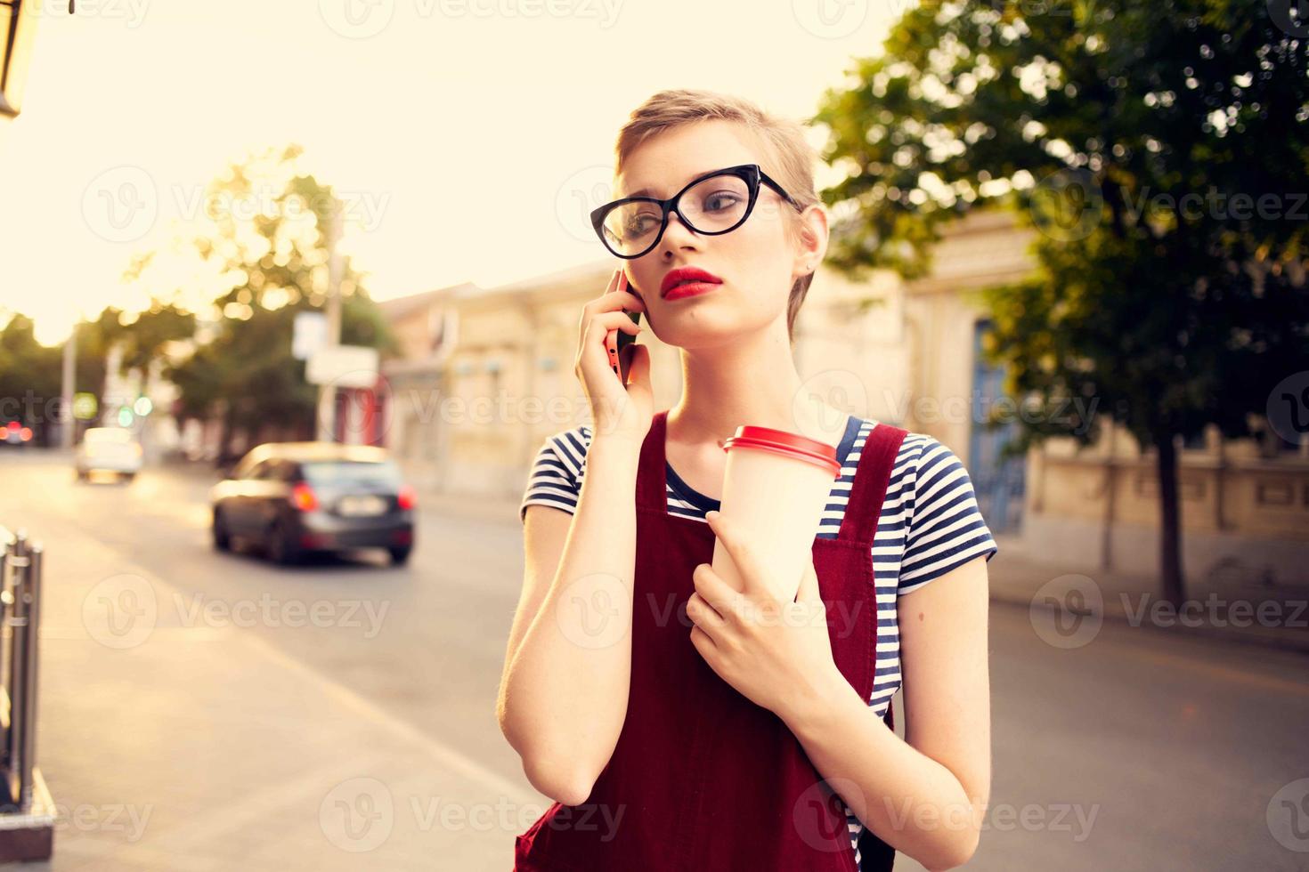 ziemlich Frau mit Brille auf das Straße reden auf das Telefon im Sommer- foto