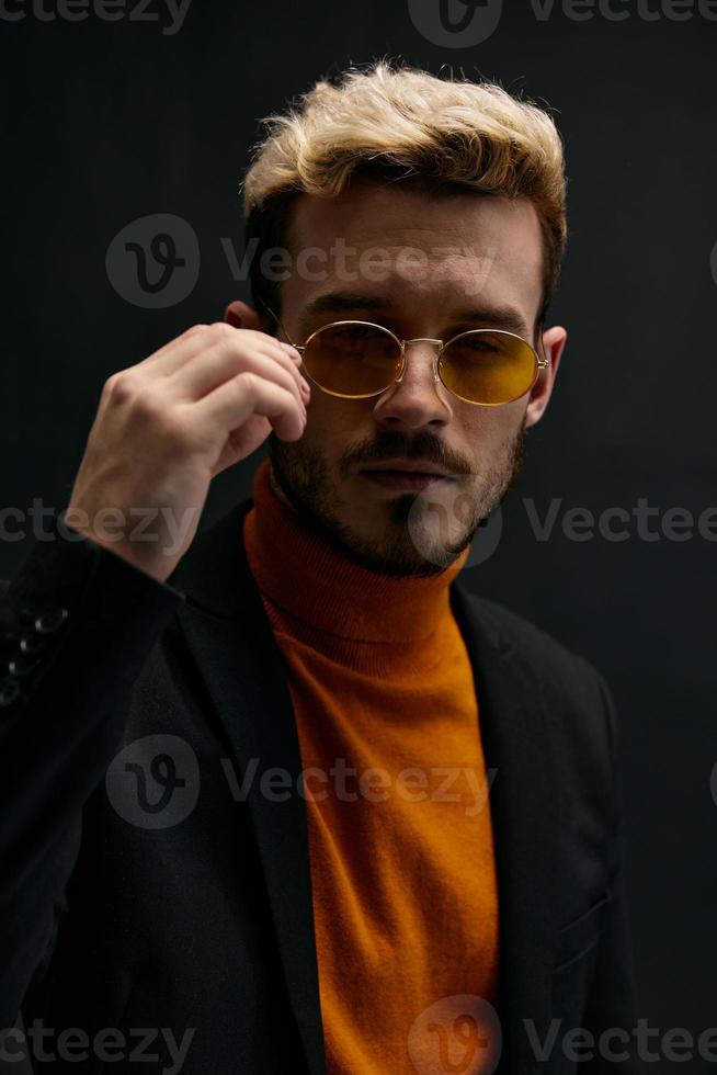 brutal Kerl mit Brille Orange Sweatshirt Mantel schwarz Hintergrund Modell- foto