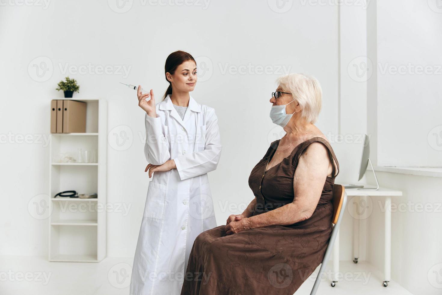 Krankenschwester geben ein Injektion zu ein Alten Frau im das Arm Immunität Schutz foto