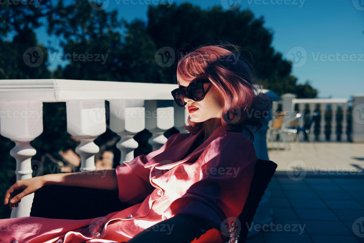 schön Frau im Sonnenbrille draußen Sitzung auf das Terrasse entspannend Entspannung Konzept foto