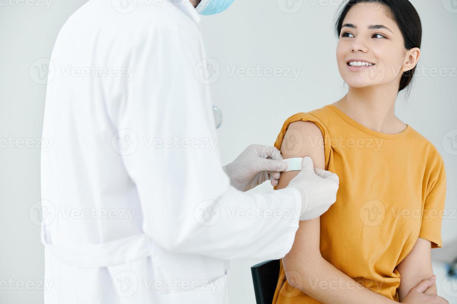 Arzt im schützend Handschuhe Bänder das Schulter von ein Frau foto