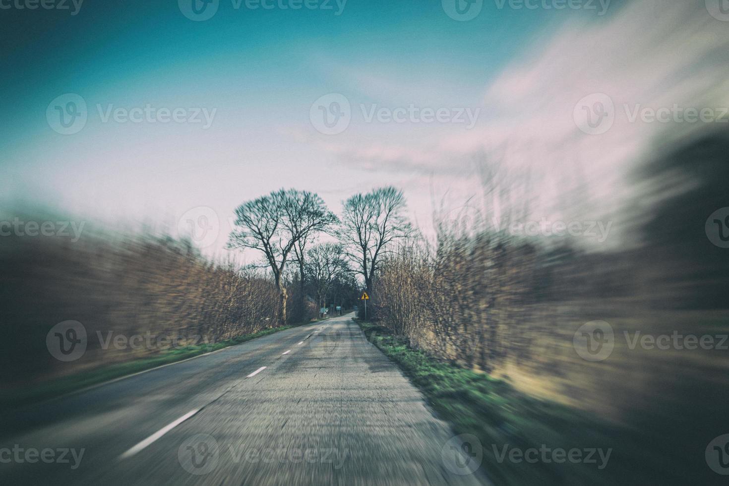 alt eng Asphalt Straße mit Bäume auf das Seite von das Straße während ein Auto Reiten im früh Frühling foto