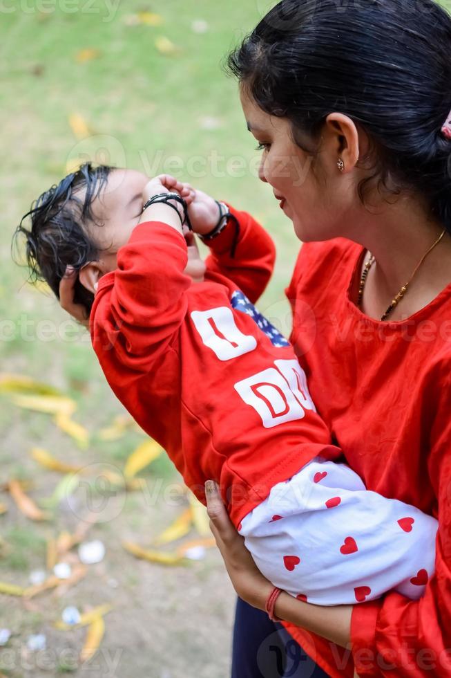 liebend Mama Tragen von ihr Baby beim Gesellschaft Park. hell Porträt von glücklich Mama halten Kind im ihr Hände. Mutter umarmen ihr wenig 9 Monate alt Sohn. foto