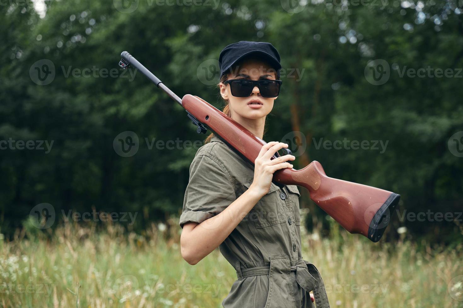 Militär- Frau im dunkel Sonnenbrille Jagd Lebensstil Waffe Grün Blätter foto