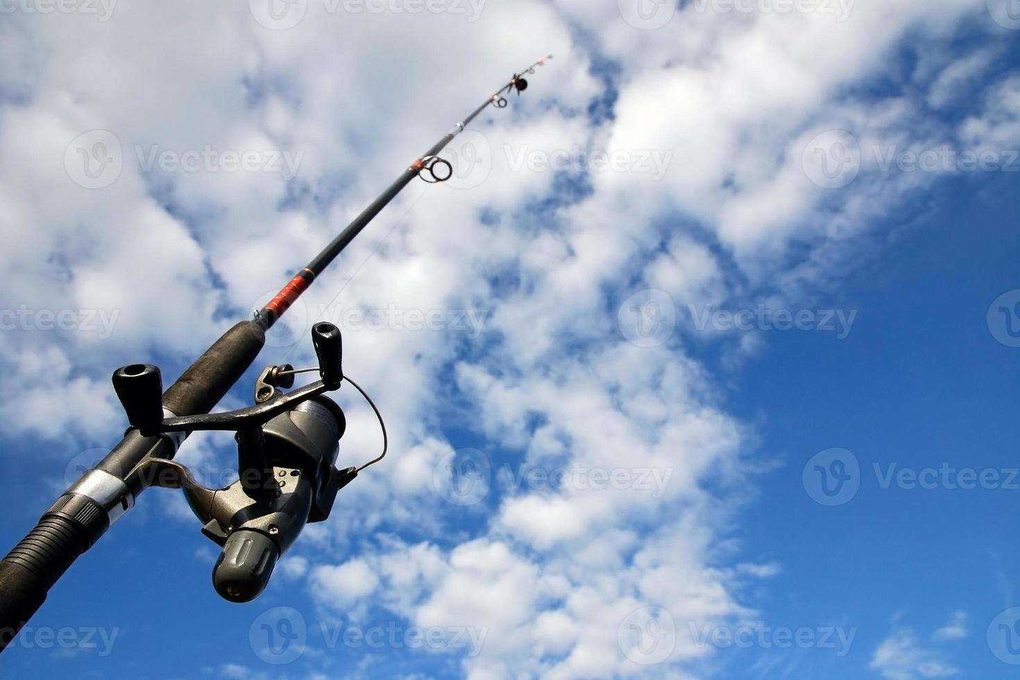 Spinnen Angeln Stange gegen Blau Himmel und Wolken. Sport Angeln, Hobby, Freizeit und Ferien foto