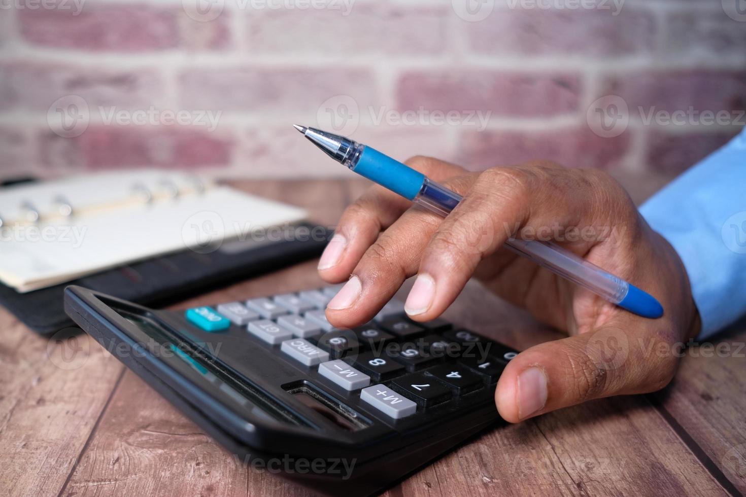 Nahaufnahme der Hand des Mannes mit Taschenrechner foto