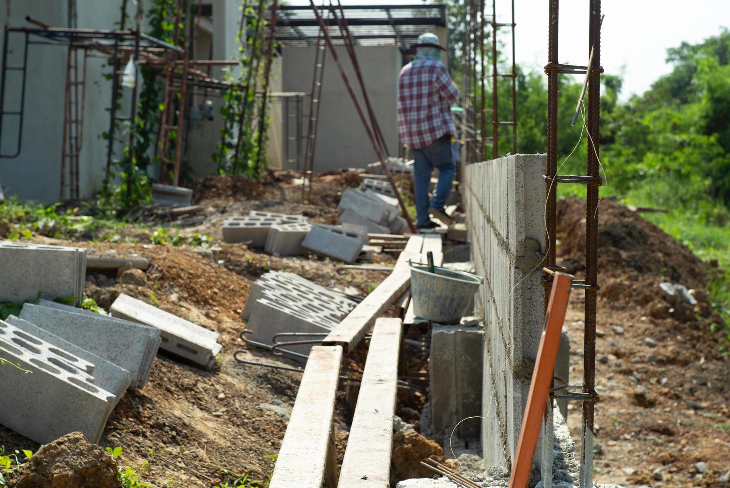 Selektiver Fokus der Mauer aus Bewehrungsstahl und Zementsteinen mit unscharfen Arbeitern im Hintergrund auf der Baustelle foto